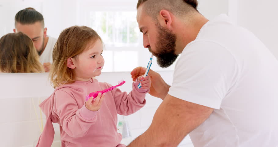 Dental health, father and girl for brushing teeth, together or laugh in bathroom in home to have fun. Oral hygiene, dad and daughter with tooth brush, being happy and bonding for learning in morning. Royalty-Free Stock Footage #1101902639
