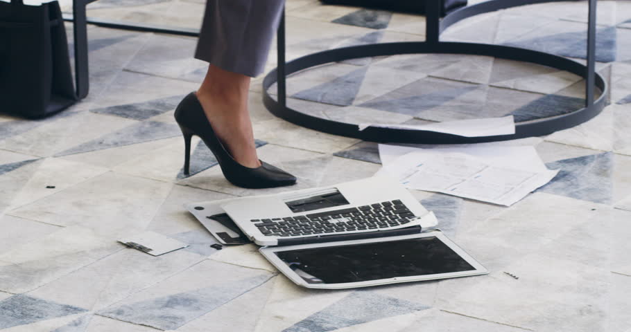 Letting out her frustrations. 4k video footage of a businesswoman breaking a laptop by jumping on it in an office. Royalty-Free Stock Footage #1101902653