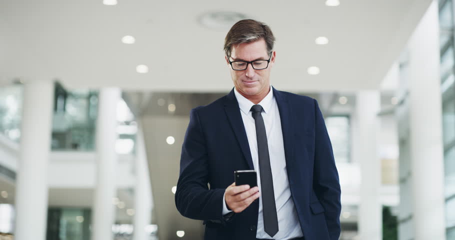 Connect to success. 4k video footage of a mature businessman using a smartphone while walking through a modern office. Royalty-Free Stock Footage #1101902731