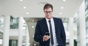 Connect to success. 4k video footage of a mature businessman using a smartphone while walking through a modern office.