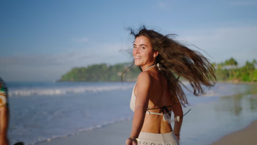 Young cheerful latin woman runs away turns to camera stretches her hand inviting her boyfriend to the sea. Happy authentic girl running from camera turns around on tropical exotic beach to ocean. POV Royalty-Free Stock Footage #1101907569