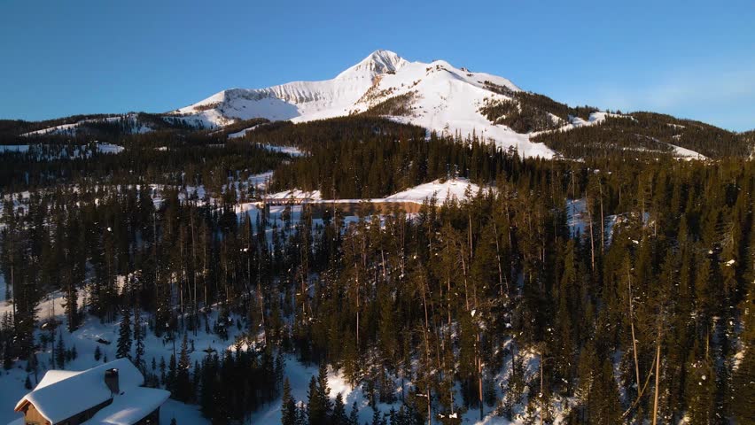 A drone shot of snowy Big Sky, Montana in winter, showcasing the ski resort and majestic mountain terrain.