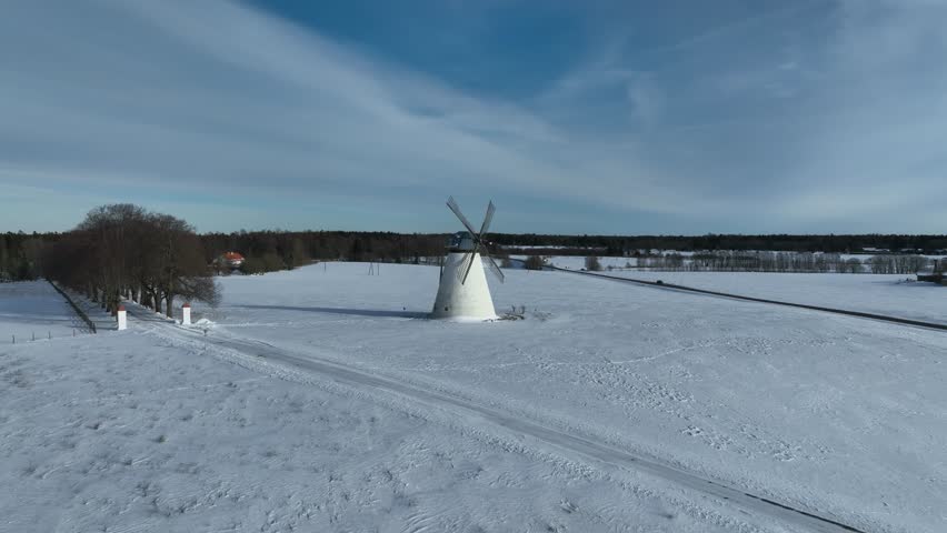 Slowly rotating aerial view of Vihula windmill in winter with white snow covering the ground, Lahemaa, Estonia.