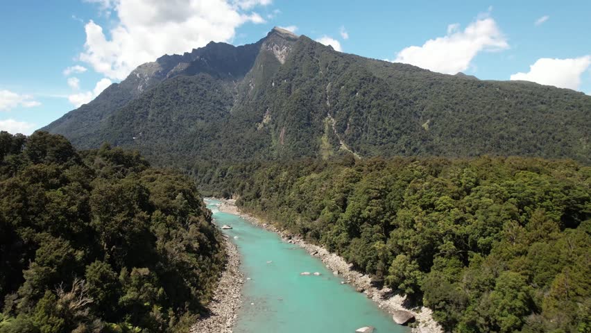 Pristine water of Copland river, native forest and mountain vista. Beautiful day in New Zealand, birds eye view.