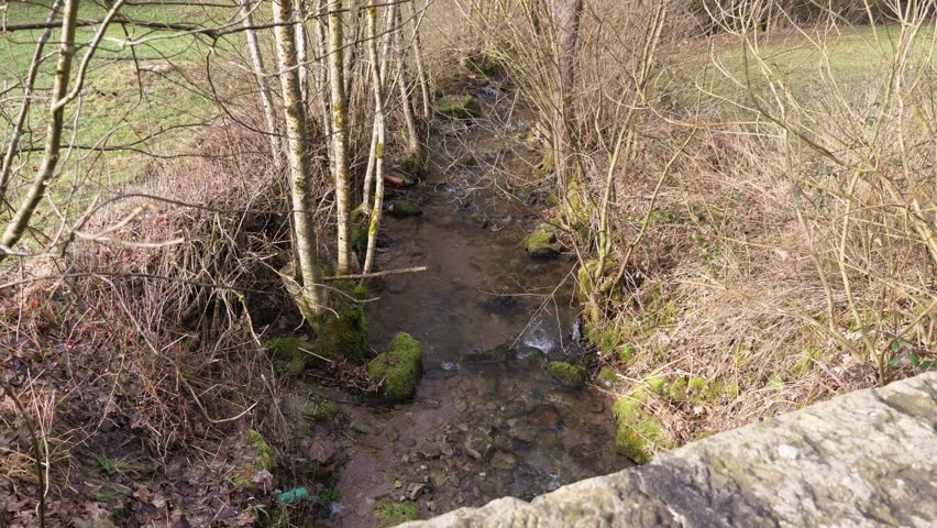 Small brook flowing under an old stone bridge