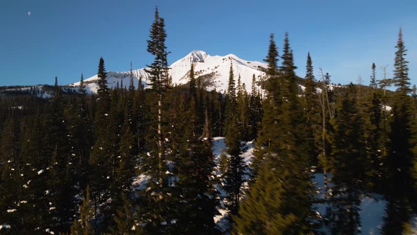 A drone shot of snowy Big Sky, Montana in winter, showcasing the ski resort and majestic mountain terrain.