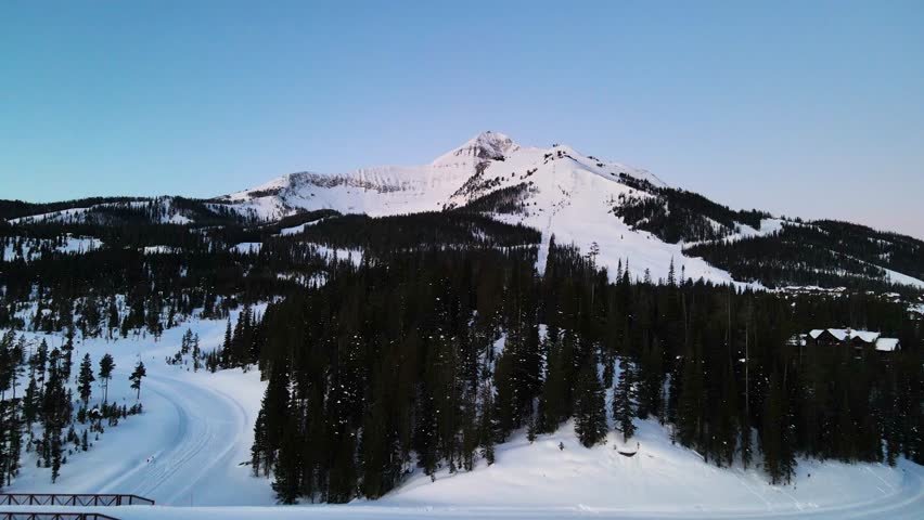 A drone shot of snowy Big Sky, Montana in winter, showcasing the ski resort and majestic mountain terrain.