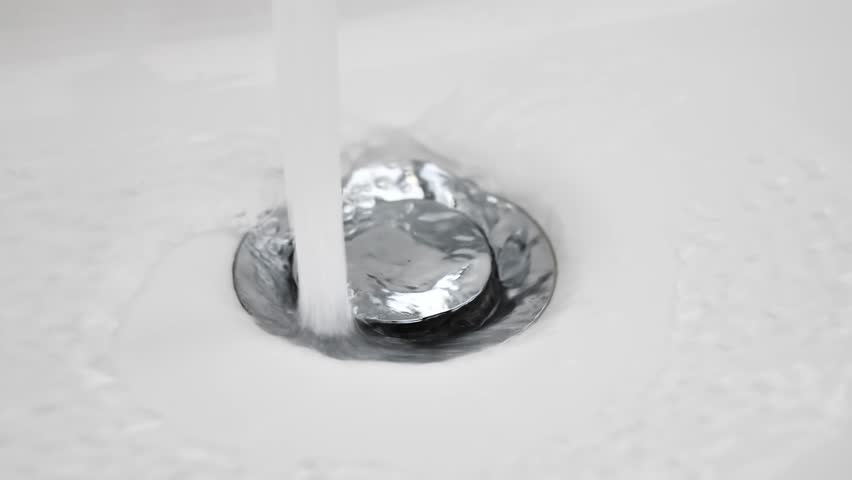 Water flows down in sink drain hole. slow motion water drain in ceramic sink. stream of water going down into drain, close up. water starts to flow and ends at end of footage. utilities. sewage | Shutterstock HD Video #1101917121