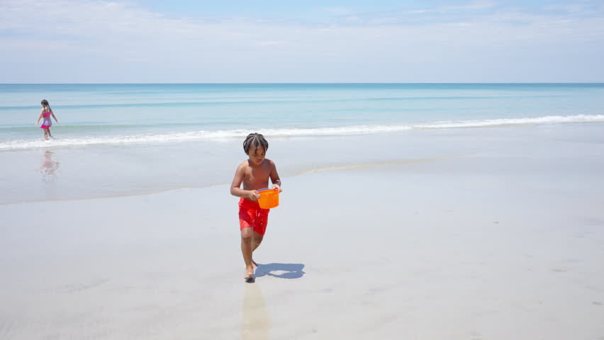 Little African child boy in swimsuit running and playing at tropical island beach in sunny day. Children kid have fun outdoor lifestyle activity travel ocean with family on summer holiday vacation.