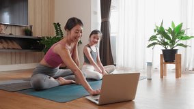 Asian Mother and Daughter Embrace Mind-Body Connection with Virtual Yoga Course on Laptop Video Call