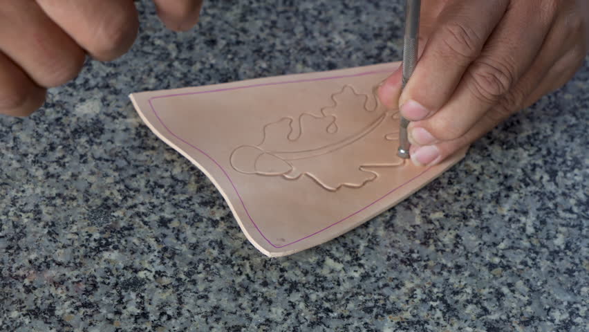 4K, Close-up hand leather craftsman who was using wooden mallet hammer leather shap had cut be pattern that drew on cow's skin, craftsman who carefully hammers cowhide make pattern look beautiful. | Shutterstock HD Video #1101926899