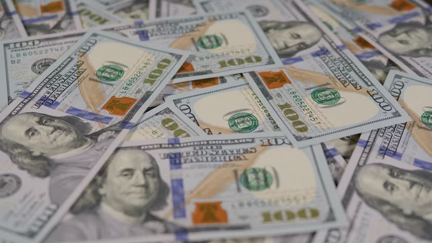 A hand in a white glove puts a silver bitcoin on stack of hundred dollar bills. Digital money, banking, investment, finance and business concept.