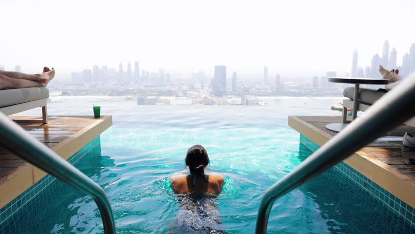 Slow motion lifestyle video of travel woman swimming in rooftop infinity pool over Dubai city skyline . Lifestyle and vacation concept on holiday | Shutterstock HD Video #1101930767