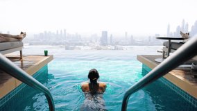 Slow motion lifestyle video of travel woman swimming in rooftop infinity pool over Dubai city skyline . Lifestyle and vacation concept on holiday