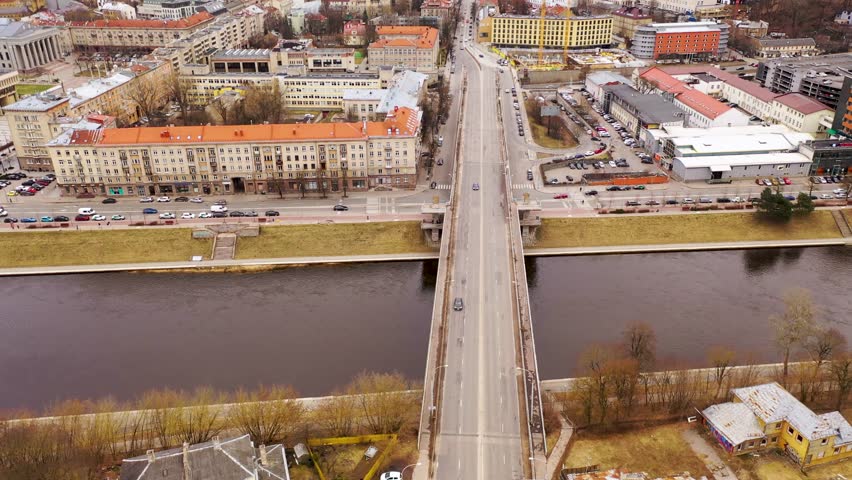Drone footage of bridge over river and cityscape during cloudy spring day. High angle view.
