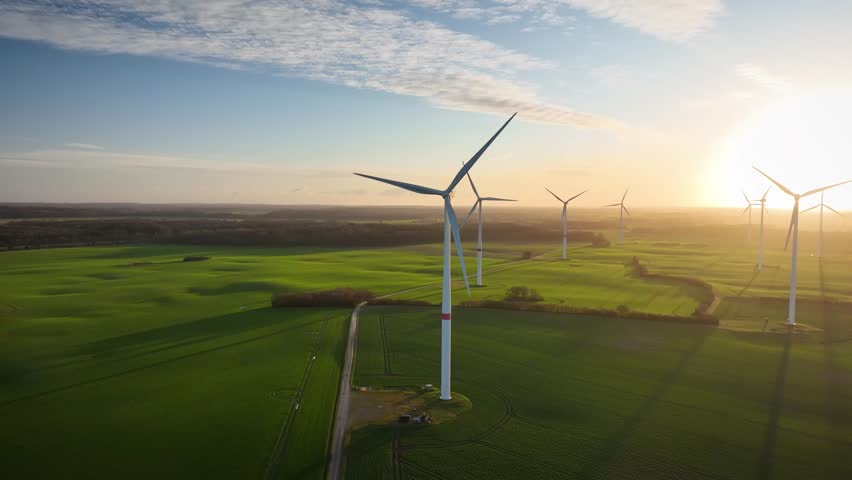 Slow camera movements around wind turbine and landscape with agricultural green fields by sunrise. Panorama of wind farm,  green field in the country side. Royalty-Free Stock Footage #1101933861