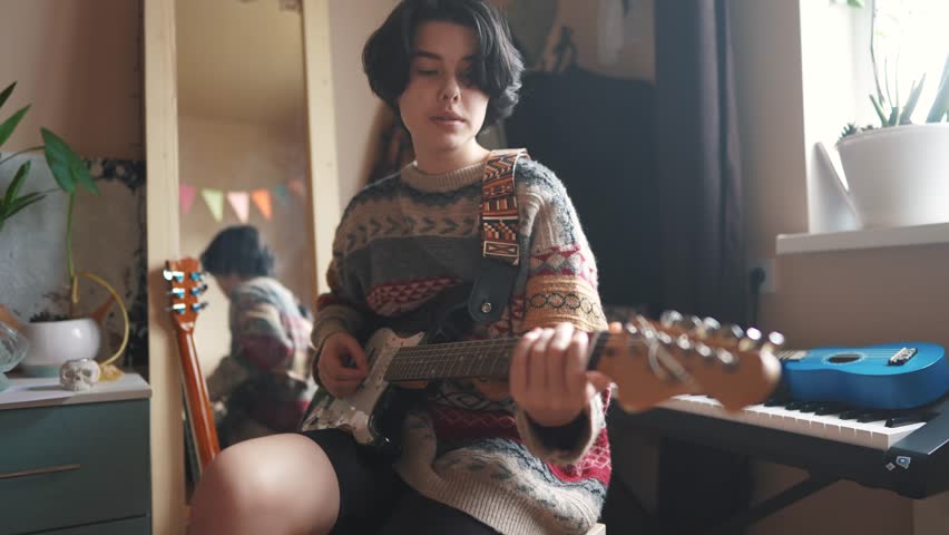 teenage girl plays electric guitar in her room. happy family music dreams concept. guitarist girl teenager. learning to play electric guitar at home. young female musician playing lifestyle guitar Royalty-Free Stock Footage #1101935409
