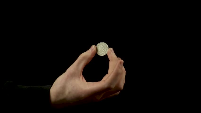Static shot of a man showing a disappearing coin trick against a black background Royalty-Free Stock Footage #1101936893