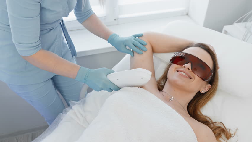 Skin care, laser hair removal in a beauty clinic. Woman cosmetologist removes body hair. Professional aesthetic skin care in a beauty clinic. Smooth and soft skin hands and feet without hair | Shutterstock HD Video #1101937667