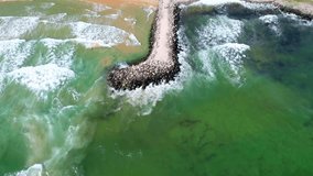 4K Drove Video - Surf of sea waves on a stone pier. Beautiful water with two natural colors. Amazing aerial view from above. Amazing aerial view on foamy waves. Cinematic footage with Color Correction