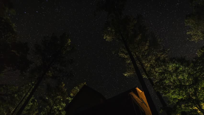 Stars over a cabin in the woods, time lapse.