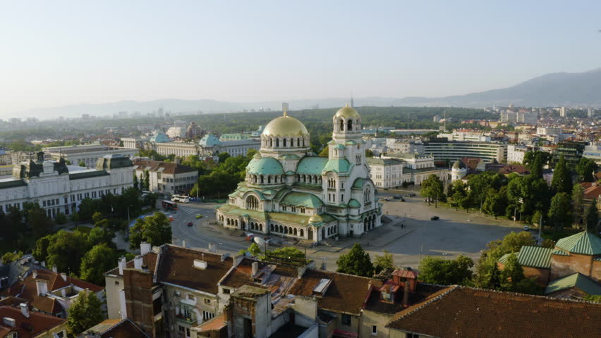 Birds flying around the drone while it orbits the St Alexander Nevsky cathedral in sunny Sofia, Bulgaria - aerial view