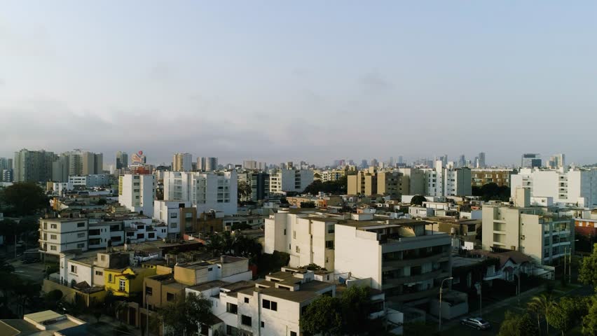 Ascending aerial view of a residential area in Lima, golden hour in Peru