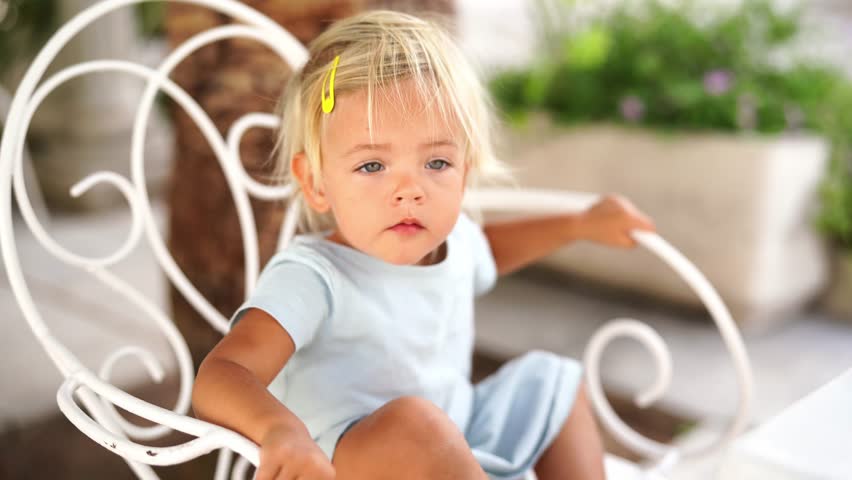 Little girl sits thoughtfully on a chair in the street
