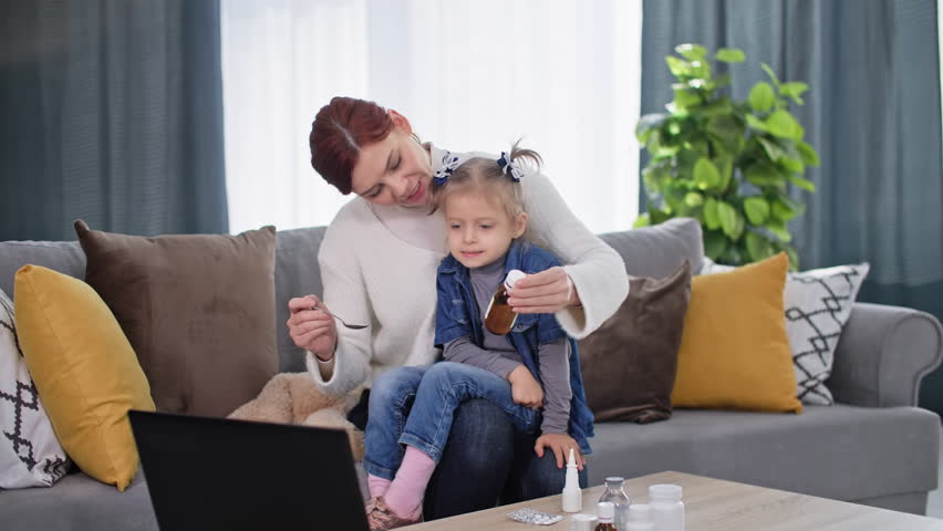 Medicine online, charming woman with little girl feeling unwell in arms talking to doctor online at home | Shutterstock HD Video #1101941519