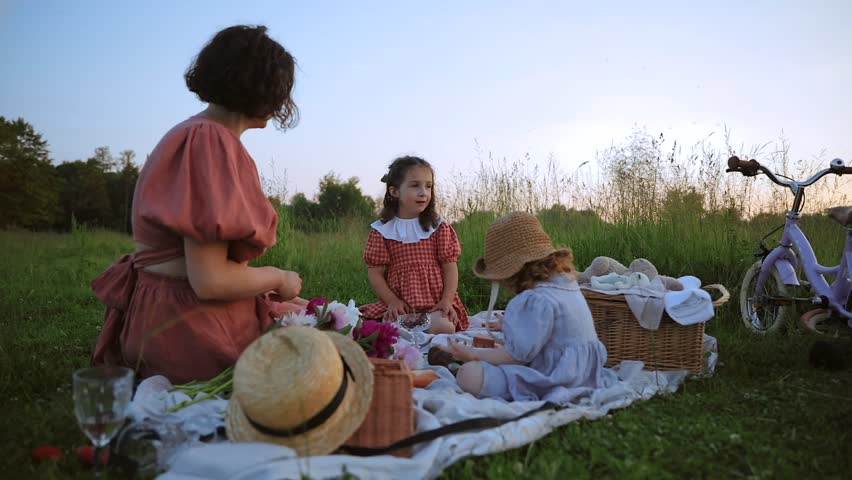 Little white red-haired girl and mother at a picnic play and make fruit decorations | Shutterstock HD Video #1101942565