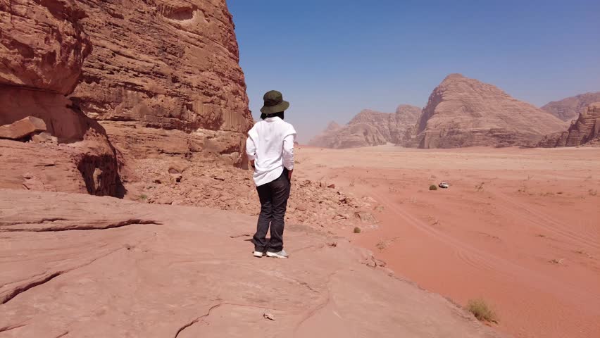 Wadi Rum, Jordan: A young Asian female tourist enjoy the view in the dramatic landscape of the Wadi Rum red desert in Jordan in the middle east. Shot with a panoramic motion