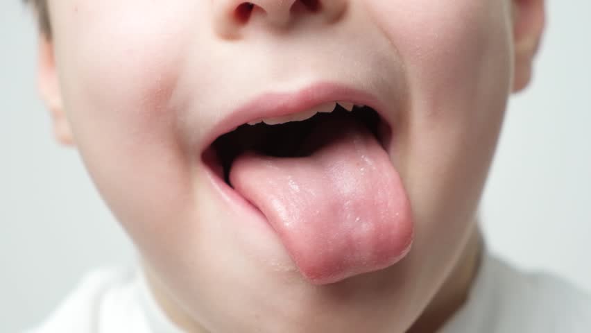 Little cute boy shows his tongue and licks, mouth close-up Royalty-Free Stock Footage #1101946399
