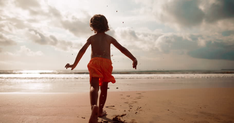 Back view of boy carefree run barefoot on the beach, slow motion Royalty-Free Stock Footage #1101951839
