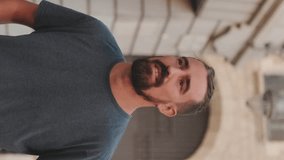 VERTICAL VIDEO, Young smiling man with beard walking and looking around at the old city background