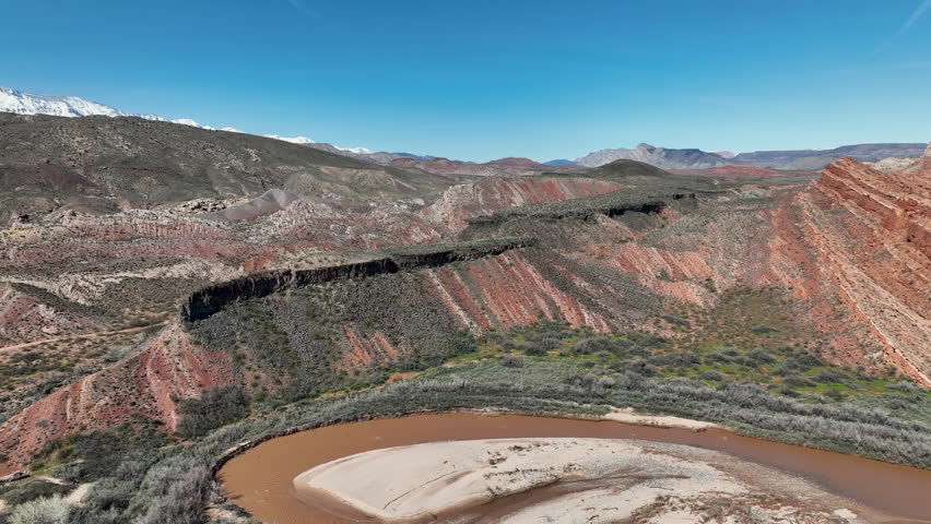 Aerial southern Utah Virgin River bend red rock mountains. Southwestern desert Utah near St George. Red stone and black volcanic mountain landscape. Geological landscape wind, weather, water erosion.