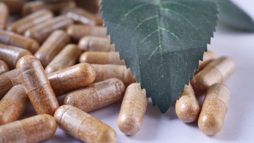 herbal medicine capsule and leaf on white 