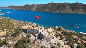 Drone video featuring Simena Castle (Kaleköy), beach, and yachts, providing a captivating view of the historical landmark and Mediterranean landscape in Antalya, Turkey.