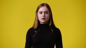 4k video of one girl showing thumb down on yellow background.