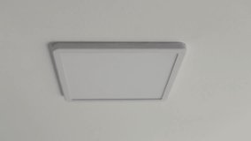 Square ceiling lamp with white daylight. Looped video. Turning on and off the lighting in the room.