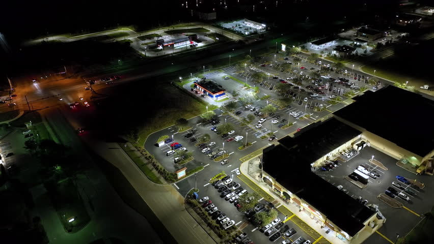 Aerial night view of many cars parked on parking lot with lines and markings for parking places and directions. Place for vehicles in front of a grocery mall store Royalty-Free Stock Footage #1101966773