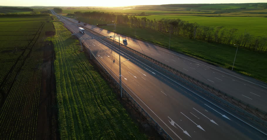 Truck driving on the highway in the rays of the setting sun. Aerial view of a car road with traffic on during sunset Royalty-Free Stock Footage #1101969883