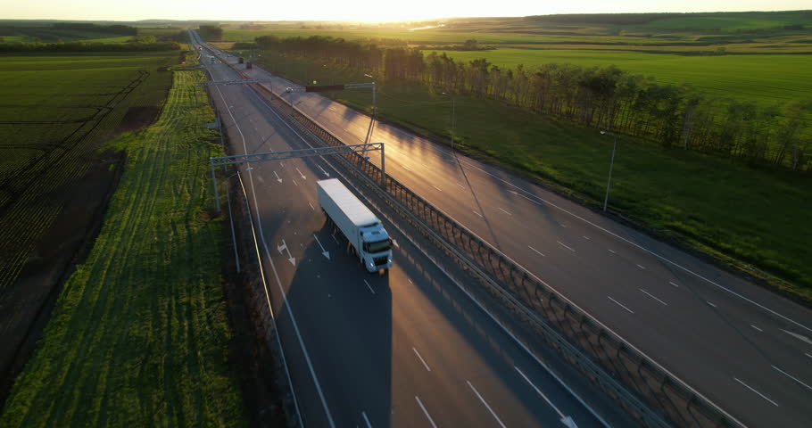 Truck driving on the highway in the rays of the setting sun. Aerial view of a car road with traffic on during sunset | Shutterstock HD Video #1101969883