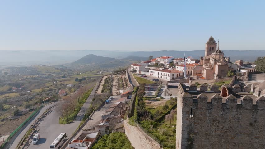 An aerial shot of the Fortress turrets on a hillside at Alcazaba de Jerez de Los Caballeros, Badajoz, Extremadura, Spain with rural mountains and hills on the horizon.