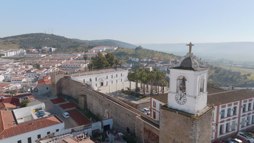 Spanish church clock tower is statue of Jesus Alcazaba de Jerez de Los Caballeros, Badajoz, Extremadura, Spain. An aerial view of the town with hill s on the horizon