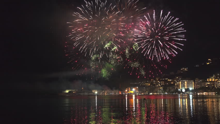 Bright fireworks exploding with colorful lights over sea shore and small mediterranean town, 4k | Shutterstock HD Video #1101980257
