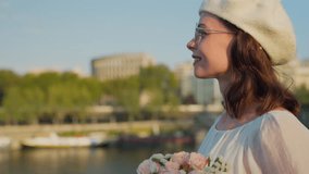 Smiling young girl with a bouquet of roses near the river Seine