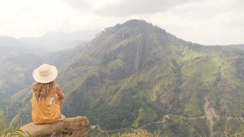 Young woman on top of beautiful green mountain valley sitting on rock arms wide open embracing nature and travel in Sri Lanka. People life success recovery concept  Royalty-Free Stock Footage #1101982089