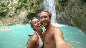SLOW MOTION: Young couple taking selfies by stunning scenic waterfall. Couple selfie point of view in nature. Travel adventure concept. - Powered by Shutterstock - Get 15% off with code: PIKWIZARD15