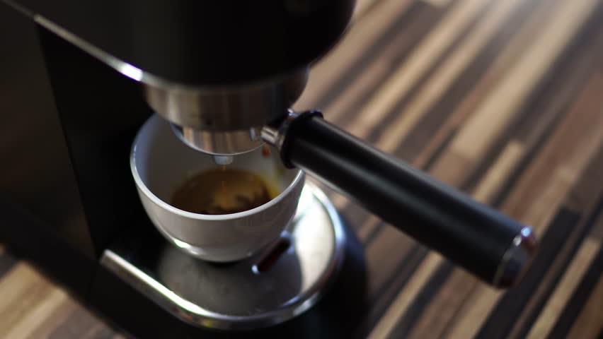 Coffee dripping from the horn of the coffee machine into the cup | Shutterstock HD Video #1101982555