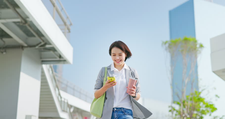 Asian happy business woman using smartphone and eco cup while walking and commuting in city Royalty-Free Stock Footage #1101986759